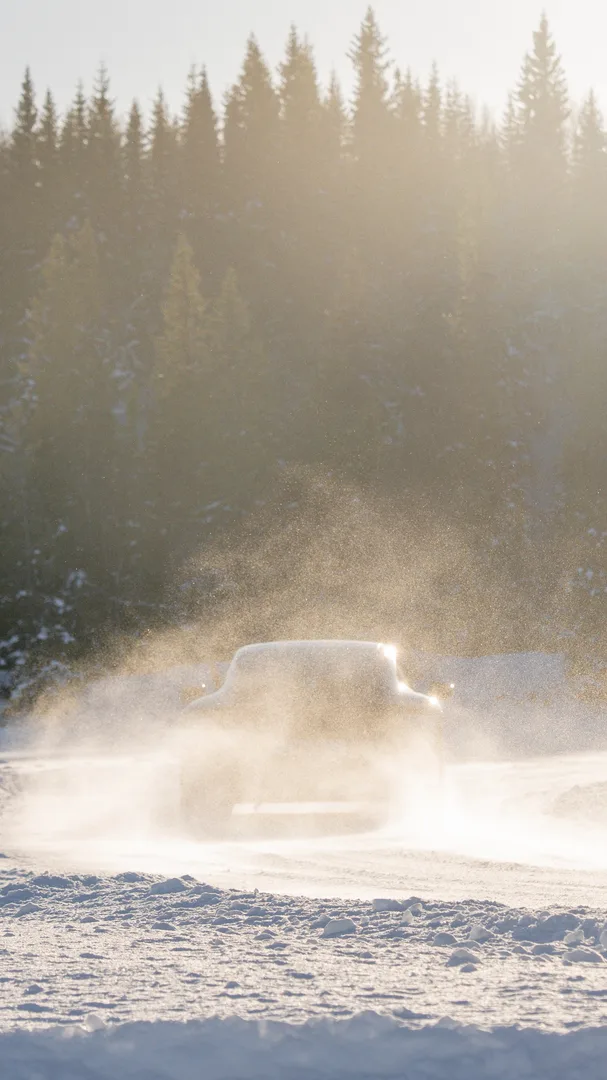 Voiture de sport en dérive dans un nuage de neige sous le soleil bas d'hiver