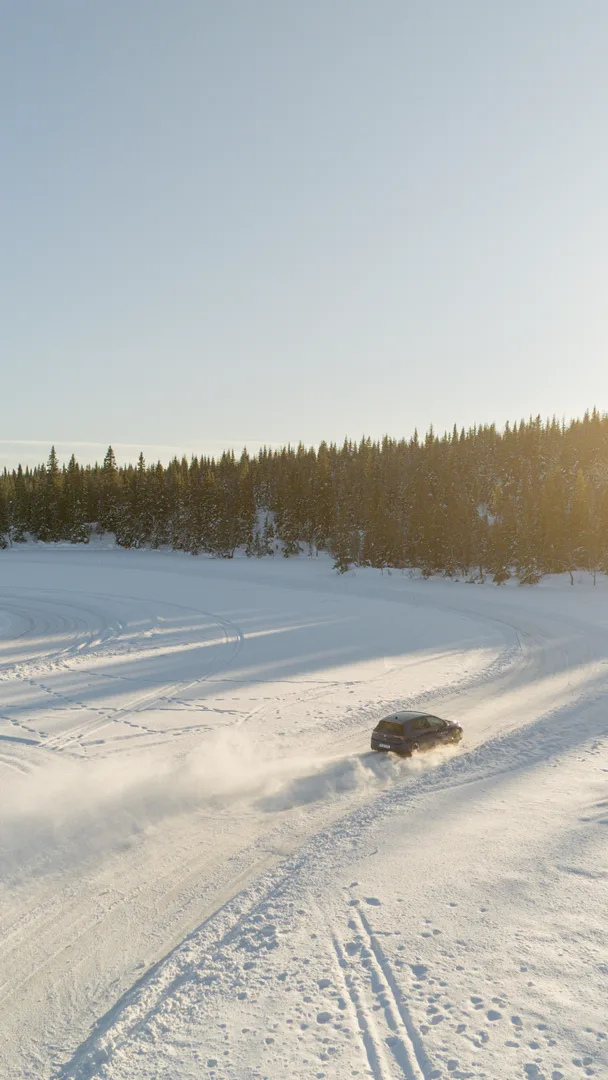 Luftaufnahme eines Autos auf einer zugefrorenen, verschneiten Piste, Skandinavien